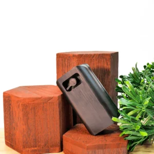 Appareil électronique compact noir TRACKD posé sur des socles en bois hexagonaux avec une plante verte.